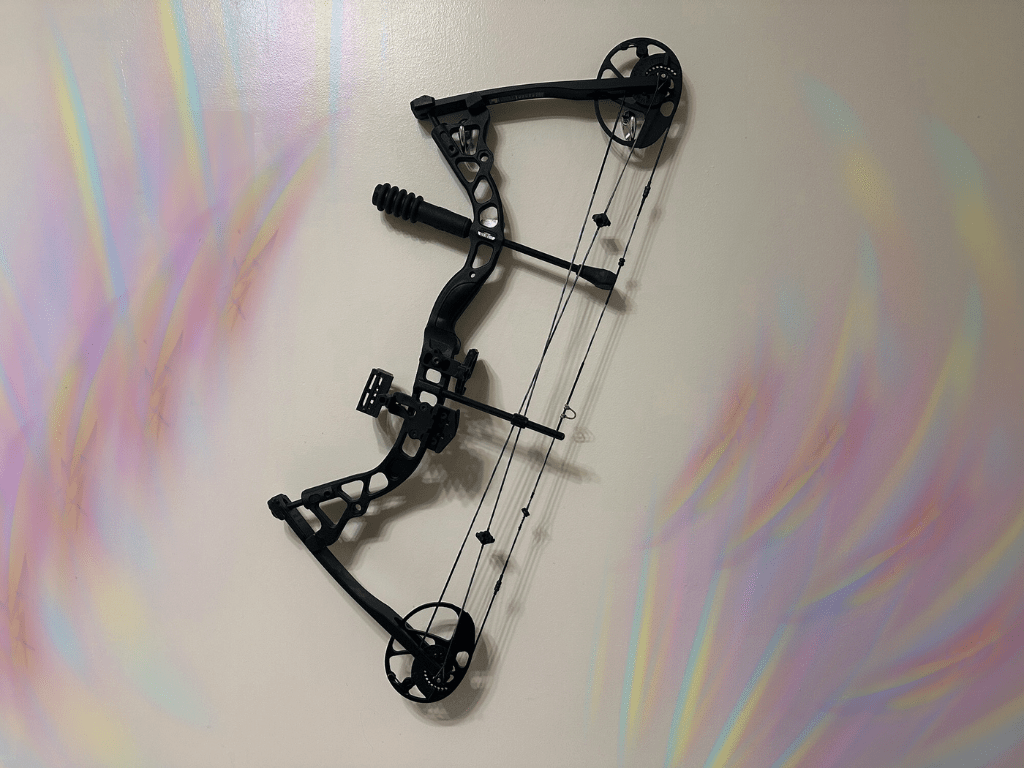 Archery bow hanging on a wall by silver hooks surrounded by a psychedelic, iridescent rainbow pattern emanating primary from its left and right sides.